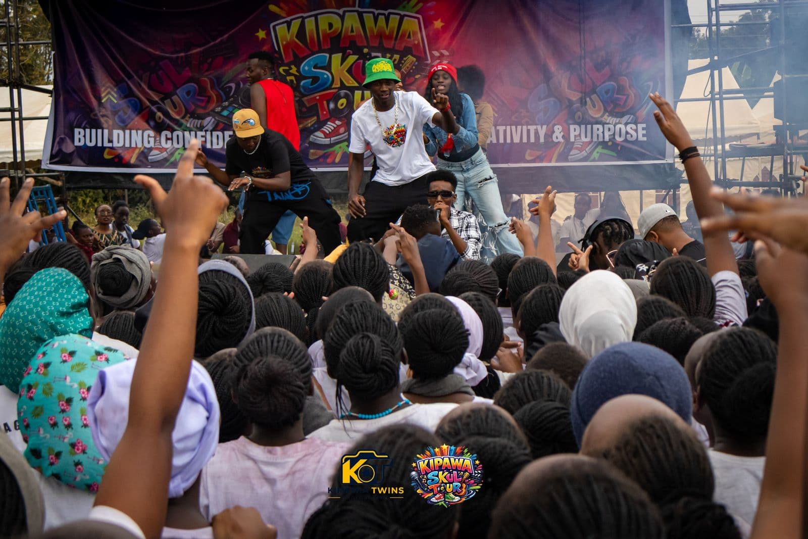 Performers on the Kipawa Skul Tour stage while students cheer with raised hands