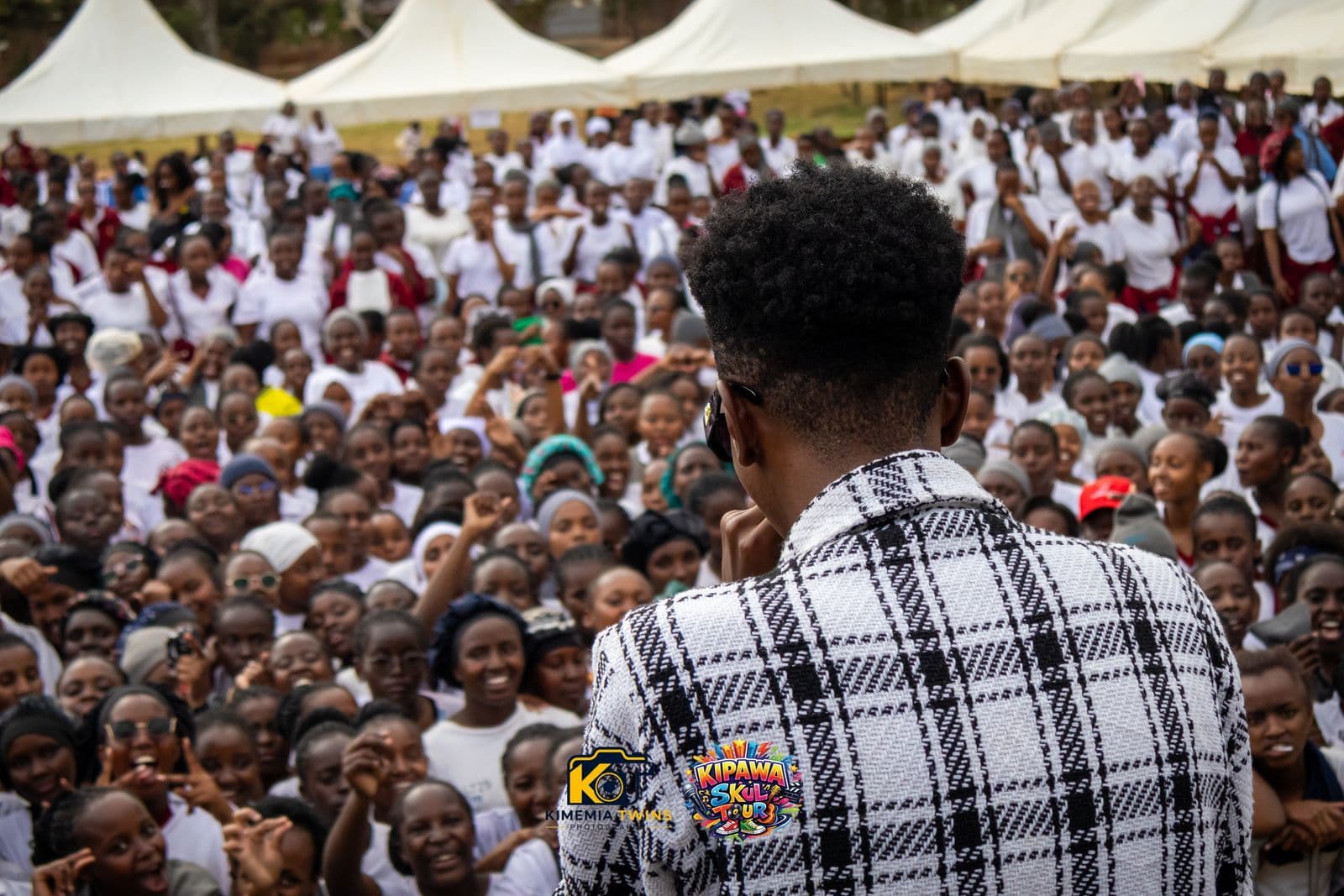 MC facing a huge crowd of students with event tents in the background