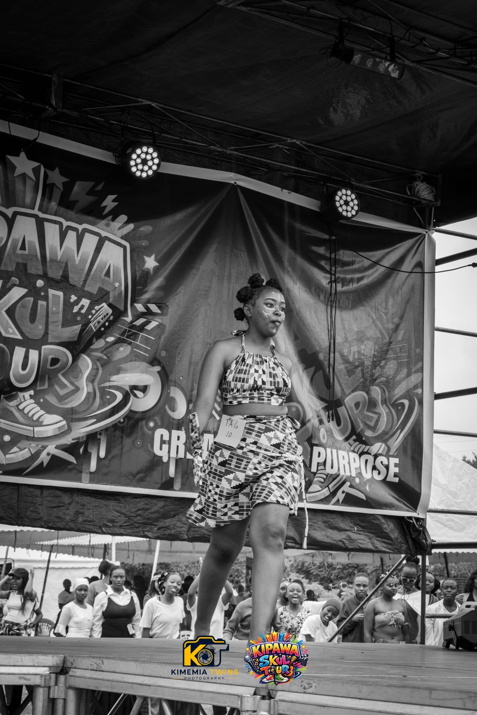 Performer in a patterned outfit on stage, black and white photo