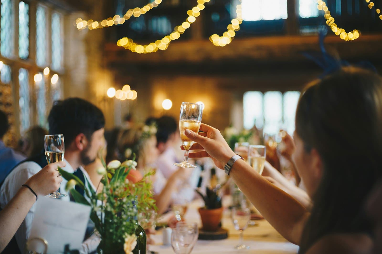 Guests raising a champagne toast under warm string lights at a private celebration