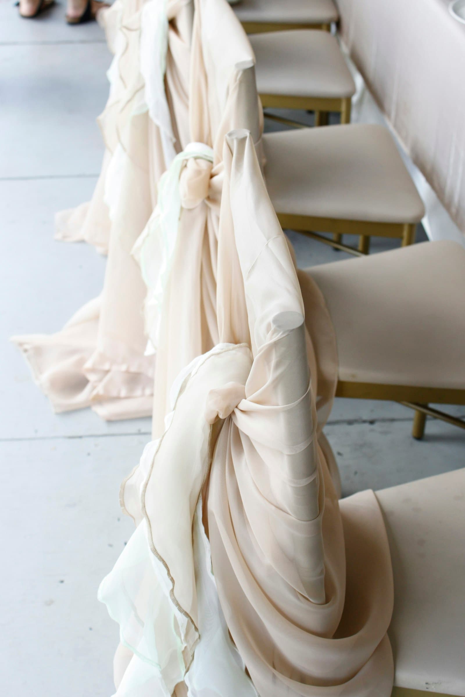 Chiavari chairs dressed with ivory sashes at a ceremony