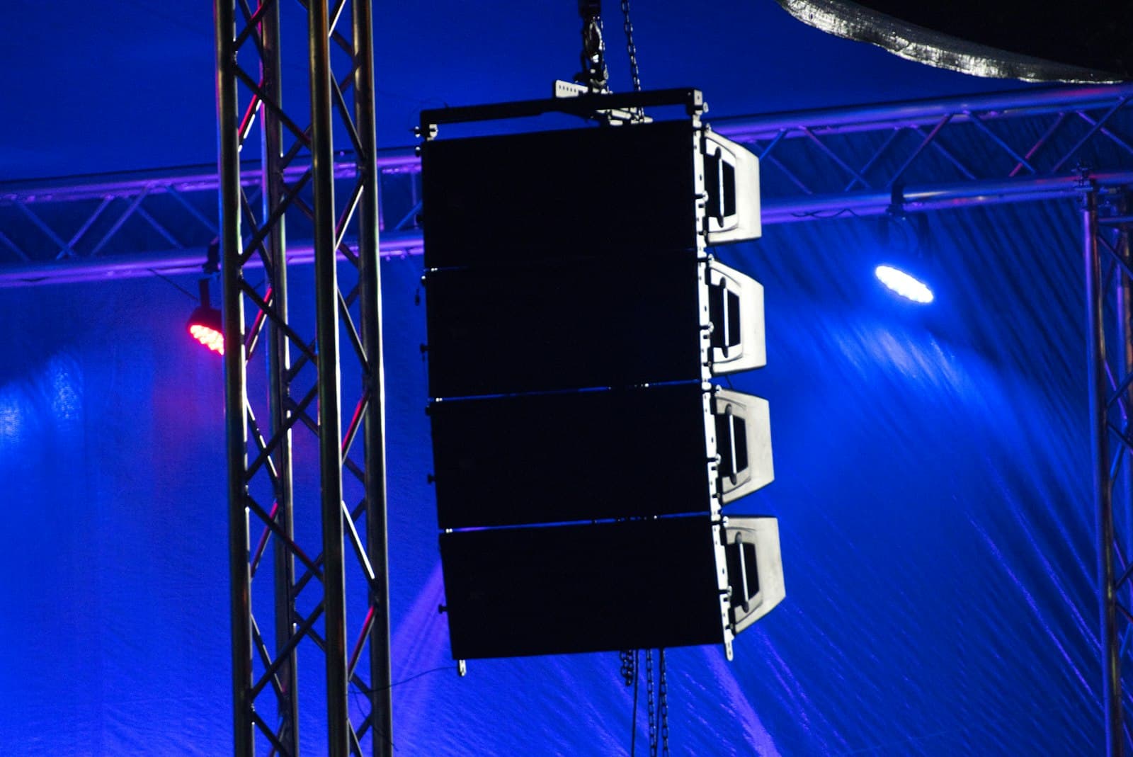 Line array PA speakers flown on truss under blue stage lighting