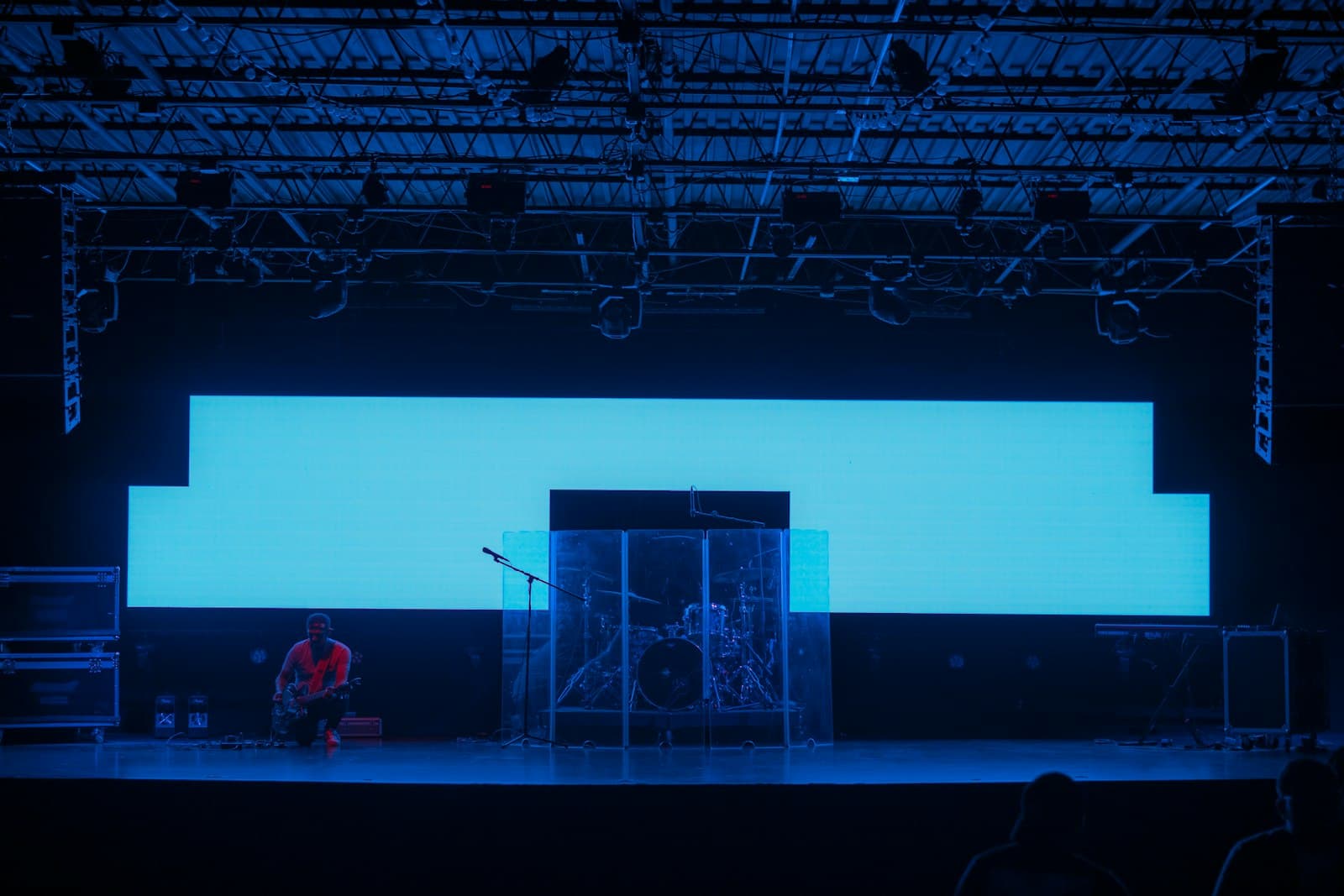 Concert stage with overhead lighting truss and a large screen