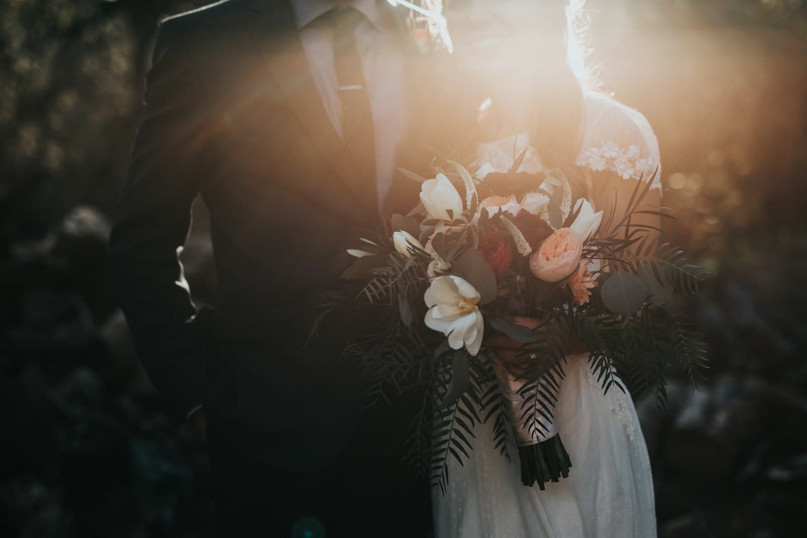 Wedding couple holding a bouquet in warm golden-hour light